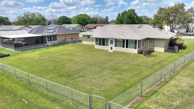 back of property featuring stucco siding, a lawn, a fenced backyard, and a gate