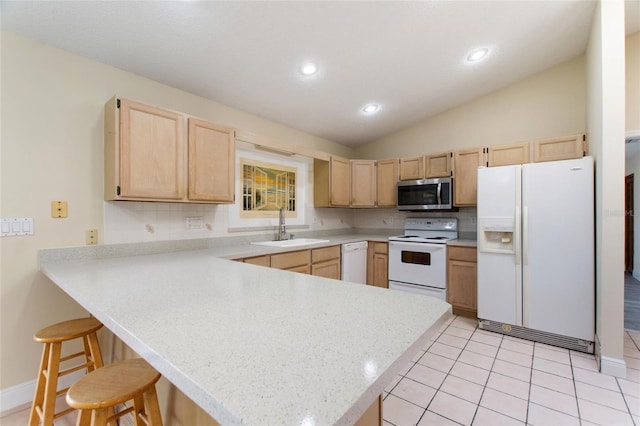 kitchen featuring light brown cabinetry, a sink, white appliances, a peninsula, and light countertops