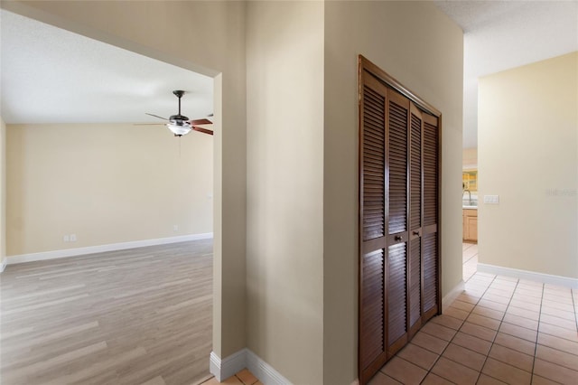 hallway featuring light tile patterned flooring, baseboards, and a sink