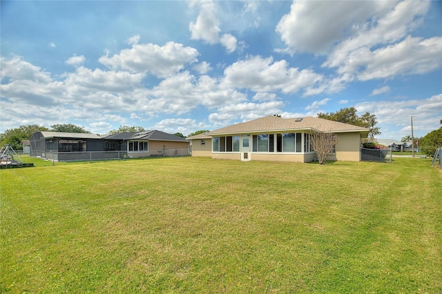 rear view of property with stucco siding, a lawn, and fence