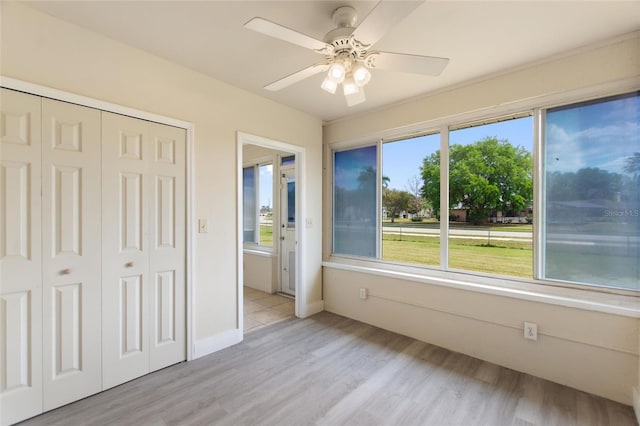 unfurnished bedroom featuring ceiling fan, a closet, and light wood-style flooring