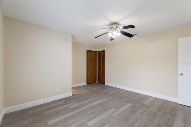 unfurnished room featuring light wood-style flooring, a textured ceiling, baseboards, and a ceiling fan