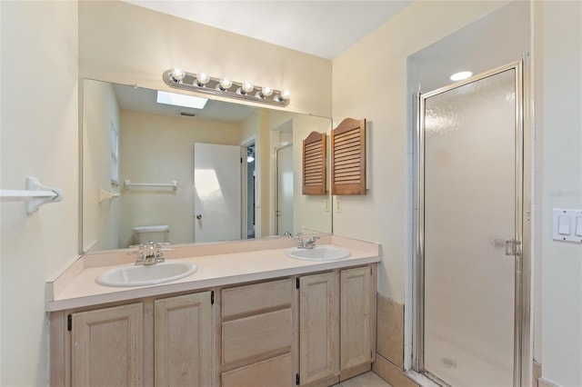 bathroom with a sink, toilet, a stall shower, and double vanity