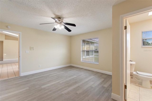 interior space featuring baseboards, a textured ceiling, light wood-style flooring, and a ceiling fan