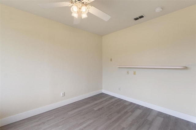 spare room featuring visible vents, baseboards, a ceiling fan, and wood finished floors