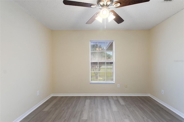 unfurnished room with a ceiling fan, wood finished floors, baseboards, and a textured ceiling