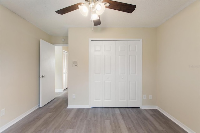 unfurnished bedroom with wood finished floors, baseboards, a closet, and ceiling fan