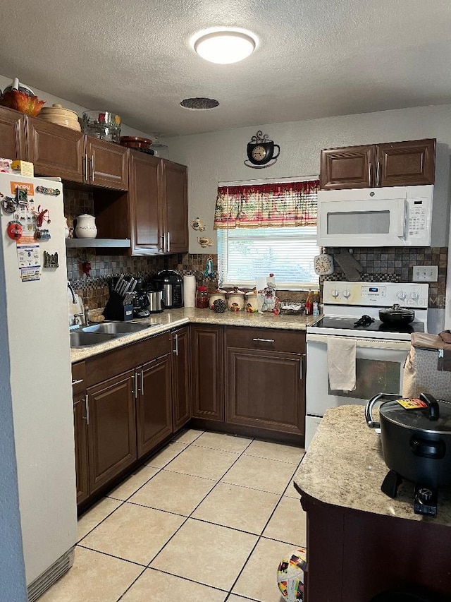 kitchen featuring tasteful backsplash, white appliances, light countertops, and a sink