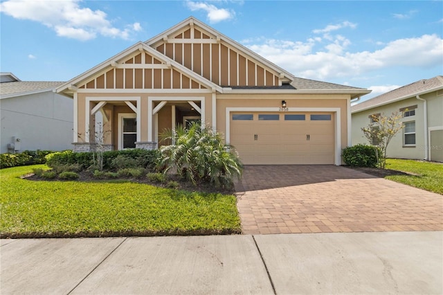 craftsman-style home with decorative driveway, an attached garage, a front lawn, and stucco siding