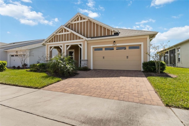 craftsman-style home featuring stucco siding, an attached garage, decorative driveway, and a front lawn