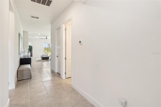 hall featuring light tile patterned floors, visible vents, and baseboards