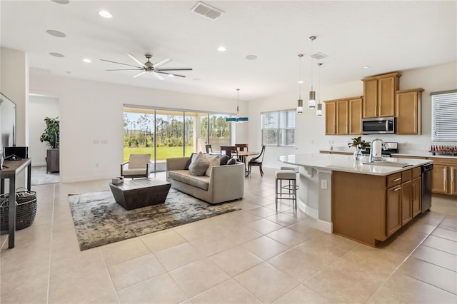 kitchen with visible vents, open floor plan, light countertops, stainless steel appliances, and a kitchen island with sink