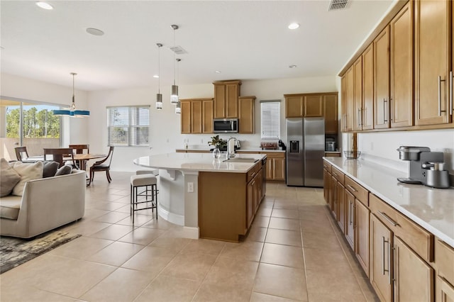 kitchen featuring light tile patterned floors, a kitchen breakfast bar, appliances with stainless steel finishes, and a sink