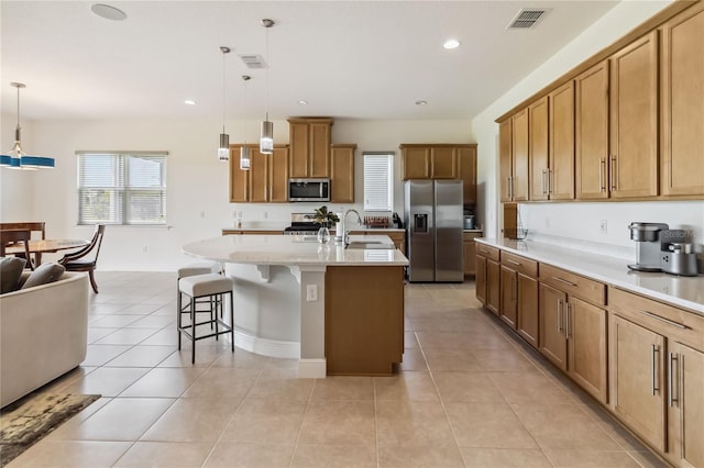 kitchen featuring visible vents, a kitchen breakfast bar, light tile patterned flooring, stainless steel appliances, and a sink