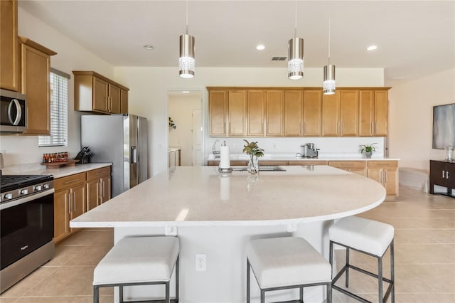 kitchen featuring light tile patterned floors, visible vents, appliances with stainless steel finishes, and a kitchen breakfast bar