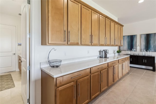 kitchen with light countertops, light tile patterned flooring, brown cabinetry, and recessed lighting