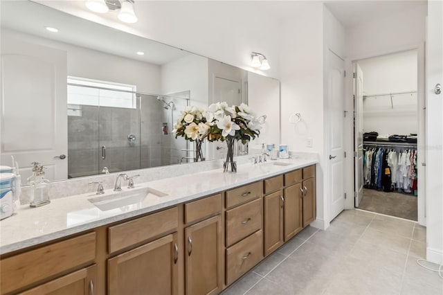 full bathroom featuring double vanity, tile patterned flooring, a shower stall, and a sink