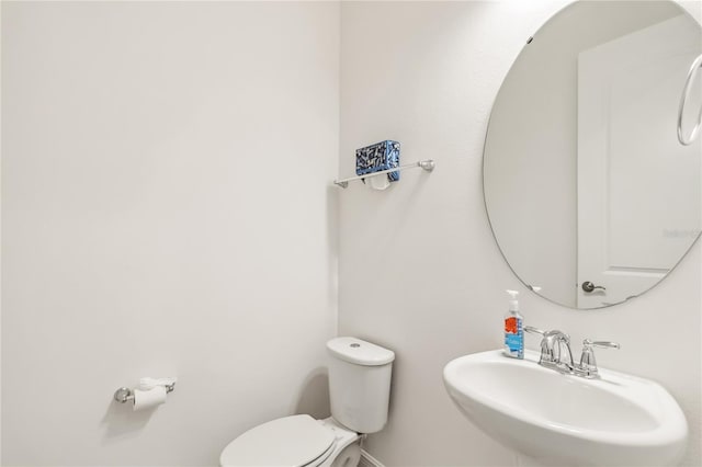 bathroom featuring a sink, baseboards, and toilet