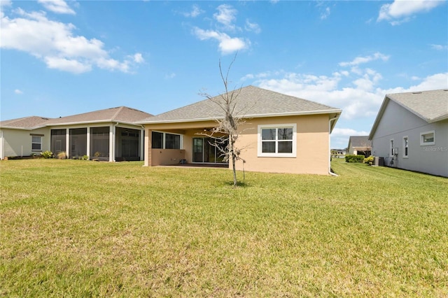 rear view of property with roof with shingles, a yard, a sunroom, and stucco siding