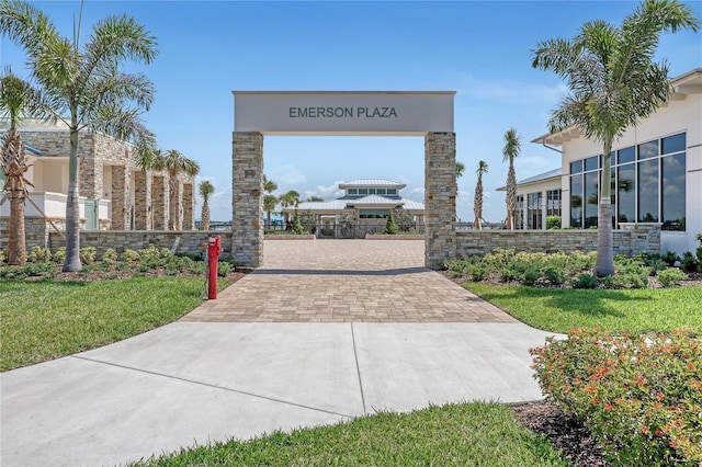 view of property's community with decorative driveway and fence