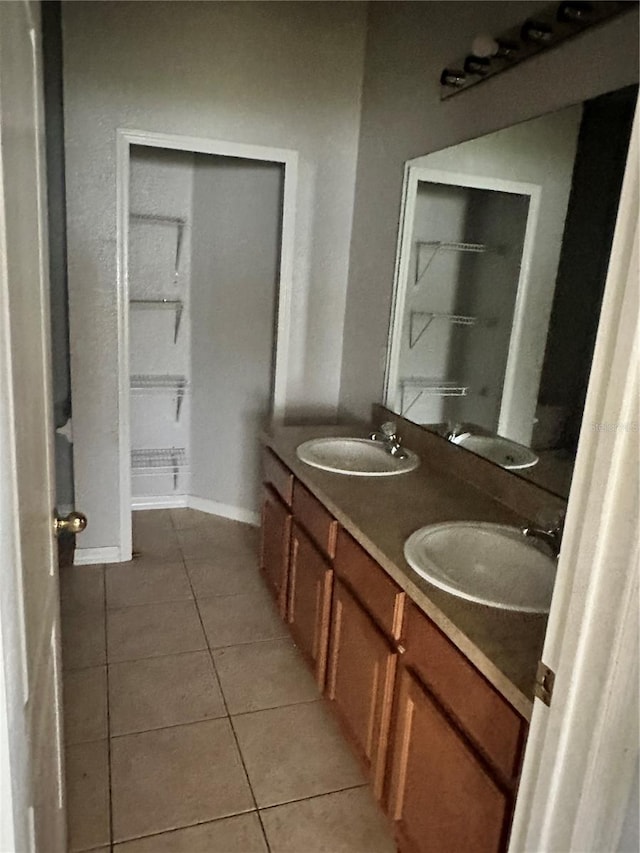 full bathroom with tile patterned floors, double vanity, baseboards, and a sink