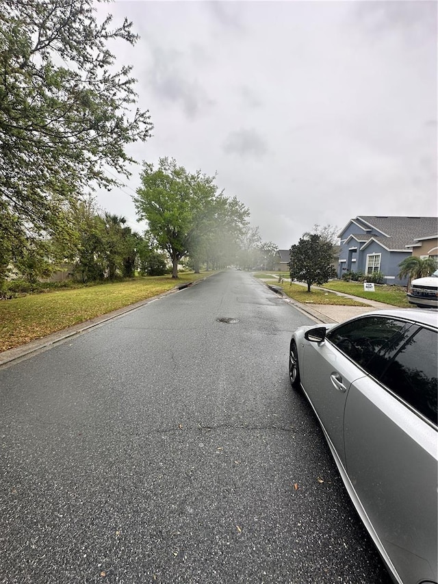 view of road with a residential view and curbs