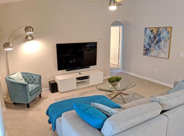 living area featuring carpet flooring, a ceiling fan, arched walkways, and baseboards