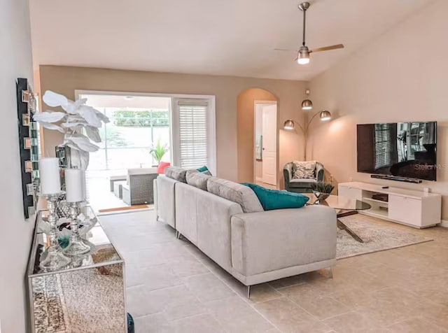 living room featuring lofted ceiling, arched walkways, and ceiling fan