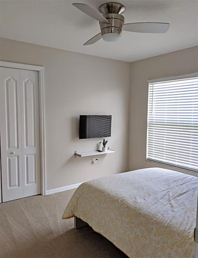 carpeted bedroom with baseboards, a closet, and ceiling fan