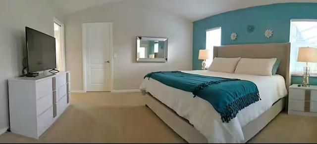 bedroom with lofted ceiling, baseboards, and light carpet