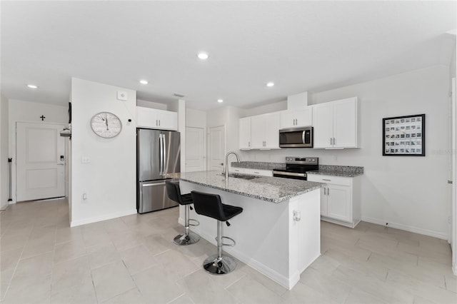 kitchen featuring white cabinets, light stone countertops, appliances with stainless steel finishes, and a sink