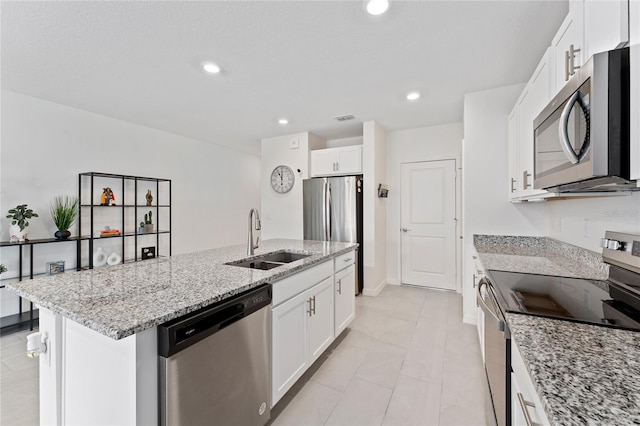 kitchen with a sink, stainless steel appliances, an island with sink, and white cabinetry