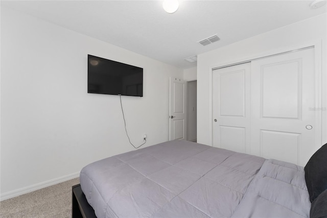 carpeted bedroom with visible vents, baseboards, and a closet