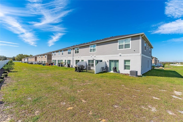 rear view of property with cooling unit and a lawn