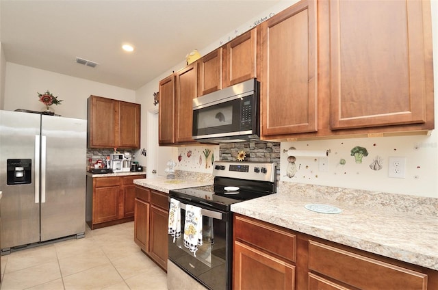 kitchen with visible vents, backsplash, stainless steel appliances, and light countertops