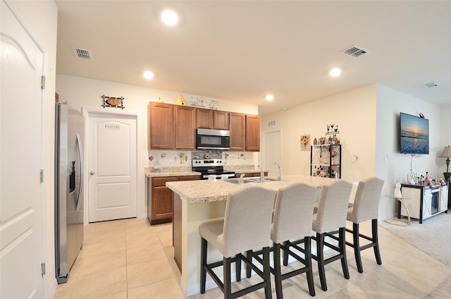 kitchen with visible vents, a breakfast bar area, light countertops, appliances with stainless steel finishes, and brown cabinetry