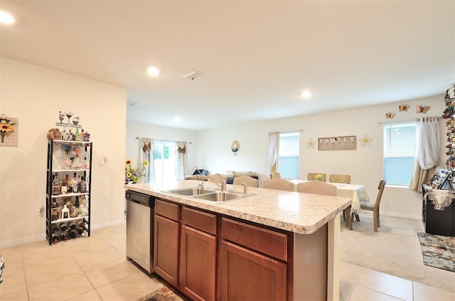 kitchen with an island with sink, a sink, plenty of natural light, light countertops, and dishwasher