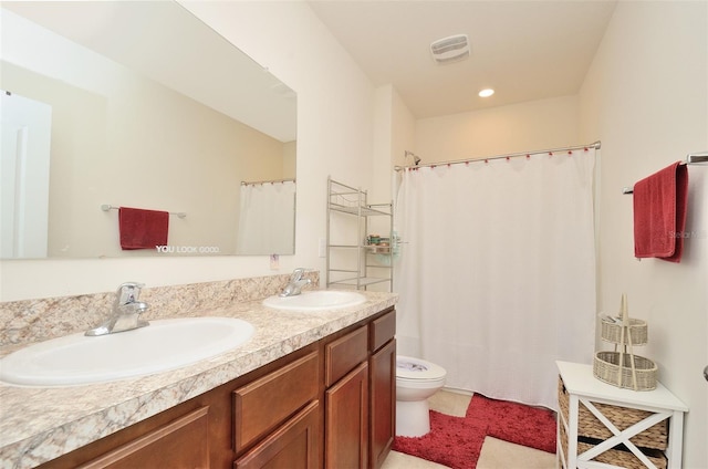 bathroom with a sink, visible vents, toilet, and double vanity