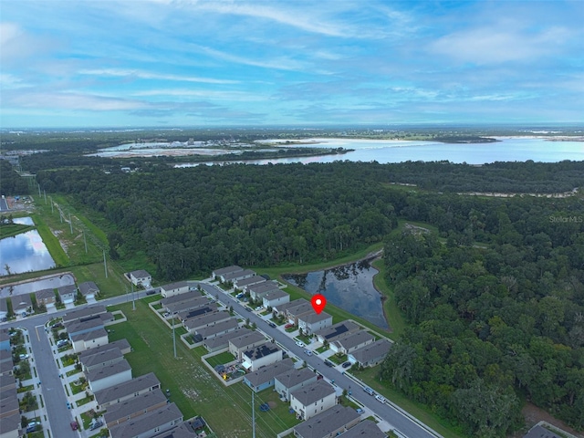 drone / aerial view featuring a residential view, a wooded view, and a water view