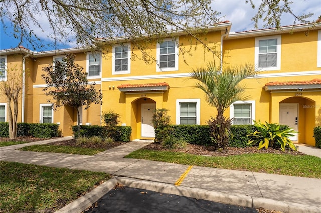 multi unit property with stucco siding and a tile roof