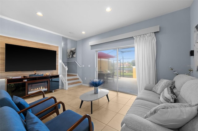 living room with a glass covered fireplace, recessed lighting, light tile patterned floors, baseboards, and stairs