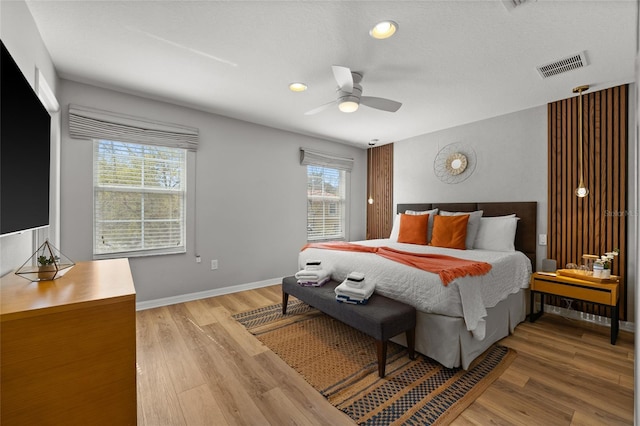 bedroom featuring visible vents, ceiling fan, light wood-type flooring, and baseboards