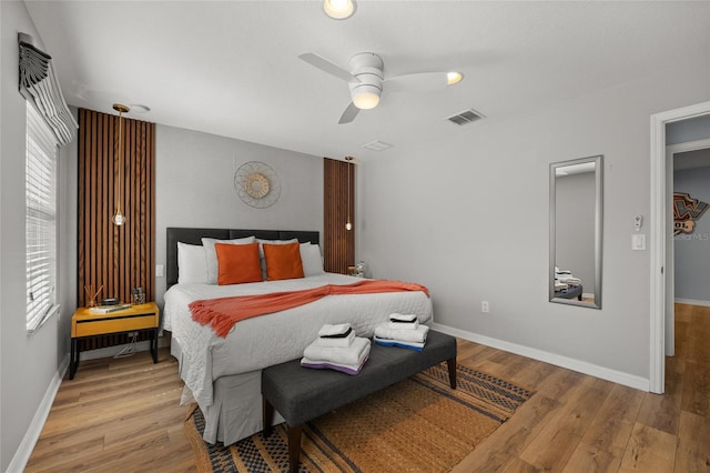 bedroom with a ceiling fan, hardwood / wood-style flooring, baseboards, and visible vents