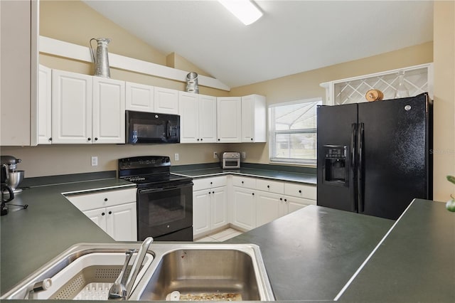 kitchen with a sink, black appliances, vaulted ceiling, white cabinetry, and dark countertops