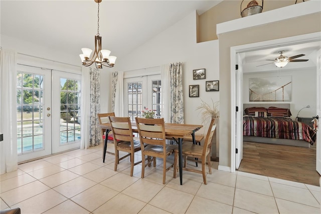 dining area with ceiling fan with notable chandelier, light tile patterned floors, french doors, and high vaulted ceiling