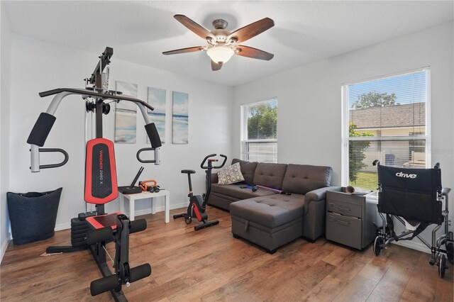 workout area with a ceiling fan, baseboards, and wood finished floors