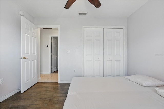 bedroom featuring dark wood-style floors, visible vents, baseboards, ceiling fan, and a closet