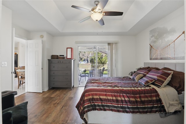 bedroom featuring hardwood / wood-style floors, a tray ceiling, access to outside, and a ceiling fan