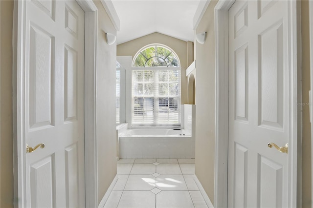 hallway with tile patterned floors, baseboards, and lofted ceiling