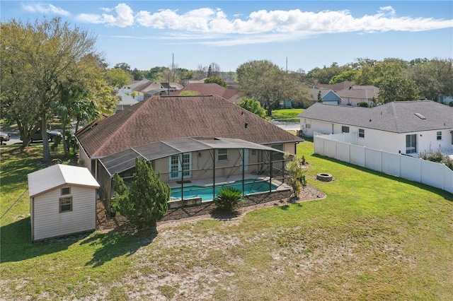 exterior space featuring a fenced in pool, a lanai, a shed, a yard, and an outbuilding